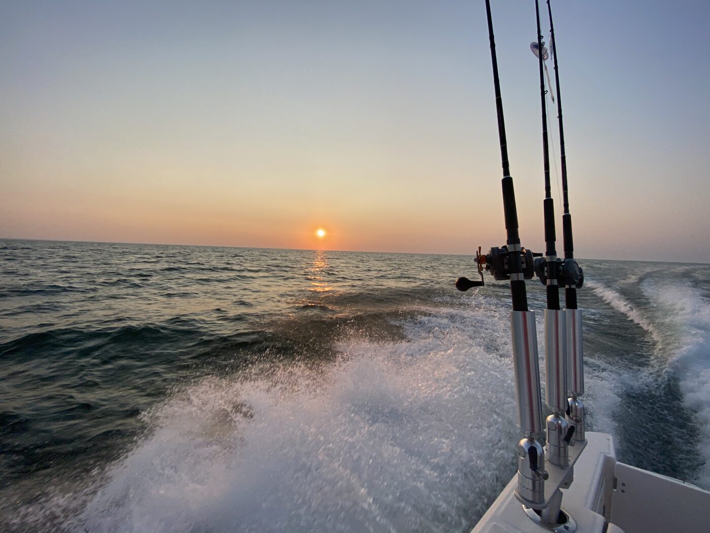 A boat wake and rod holders at first light